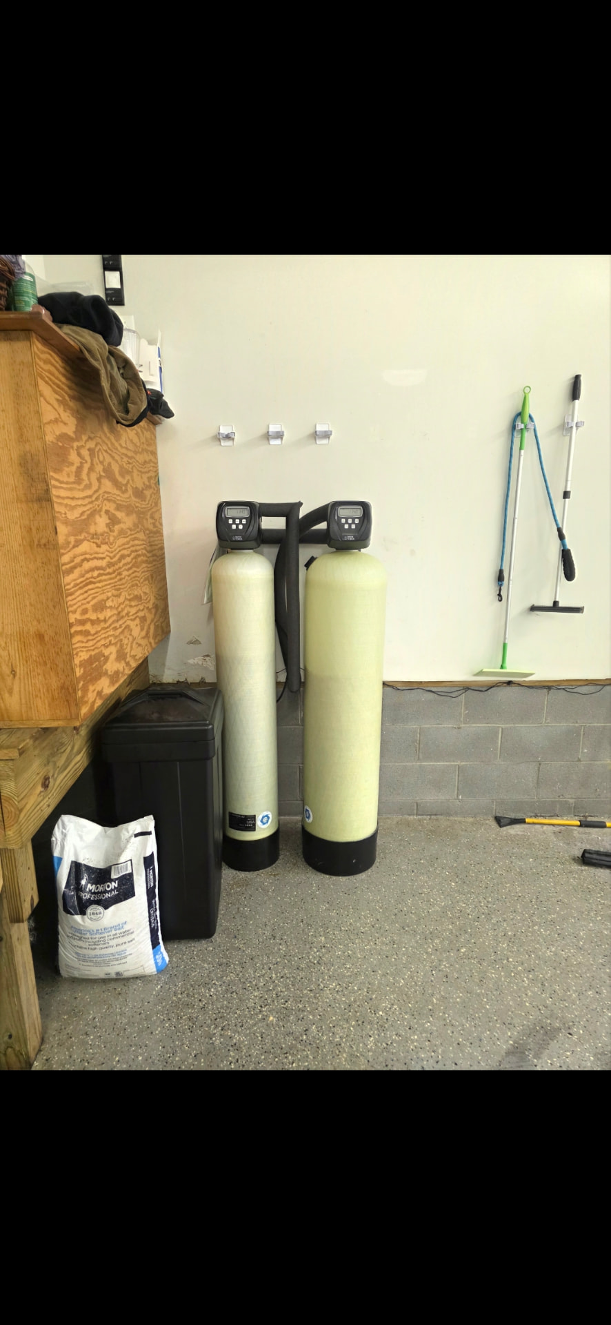 Twin water softener and filtration tanks installed in a garage