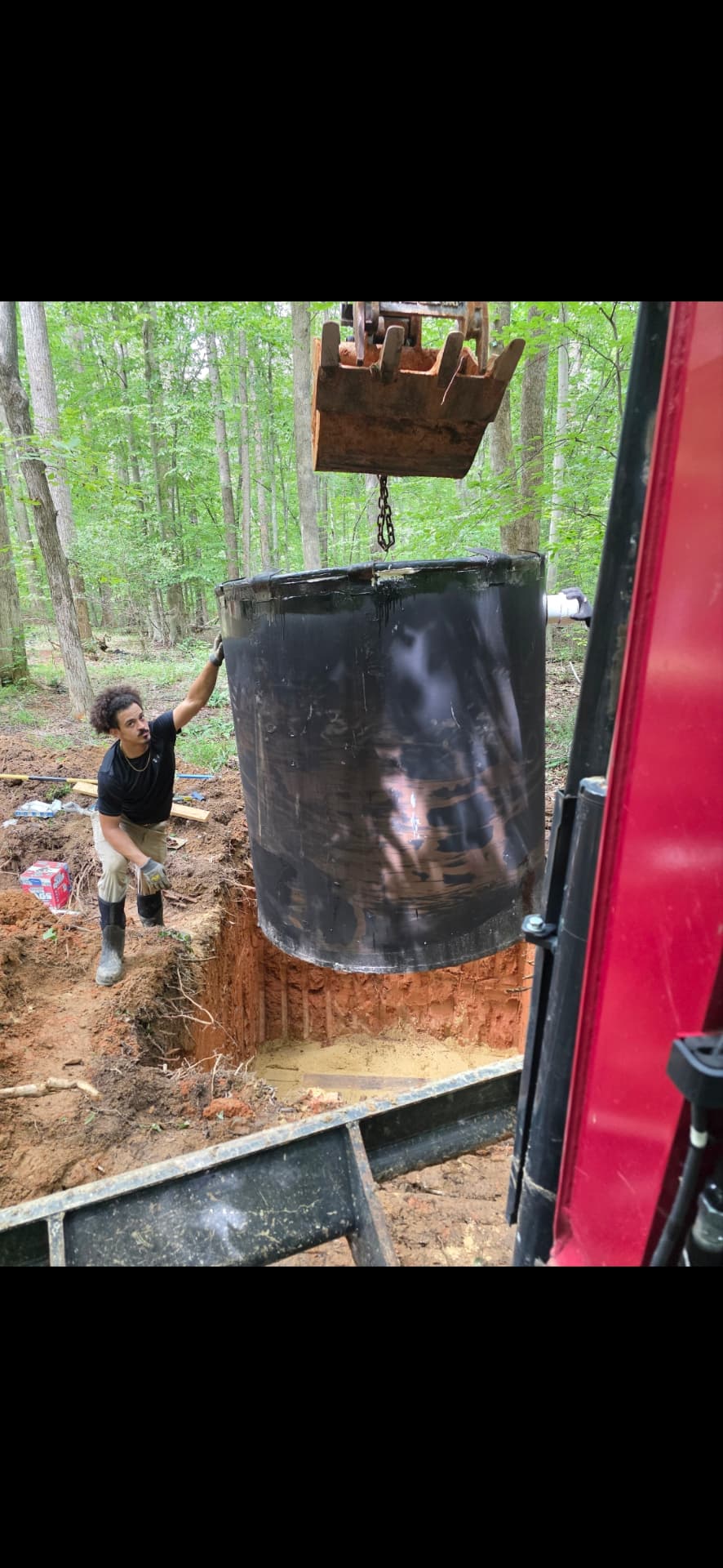 Underground tank being lowered into an excavated pit with equipment