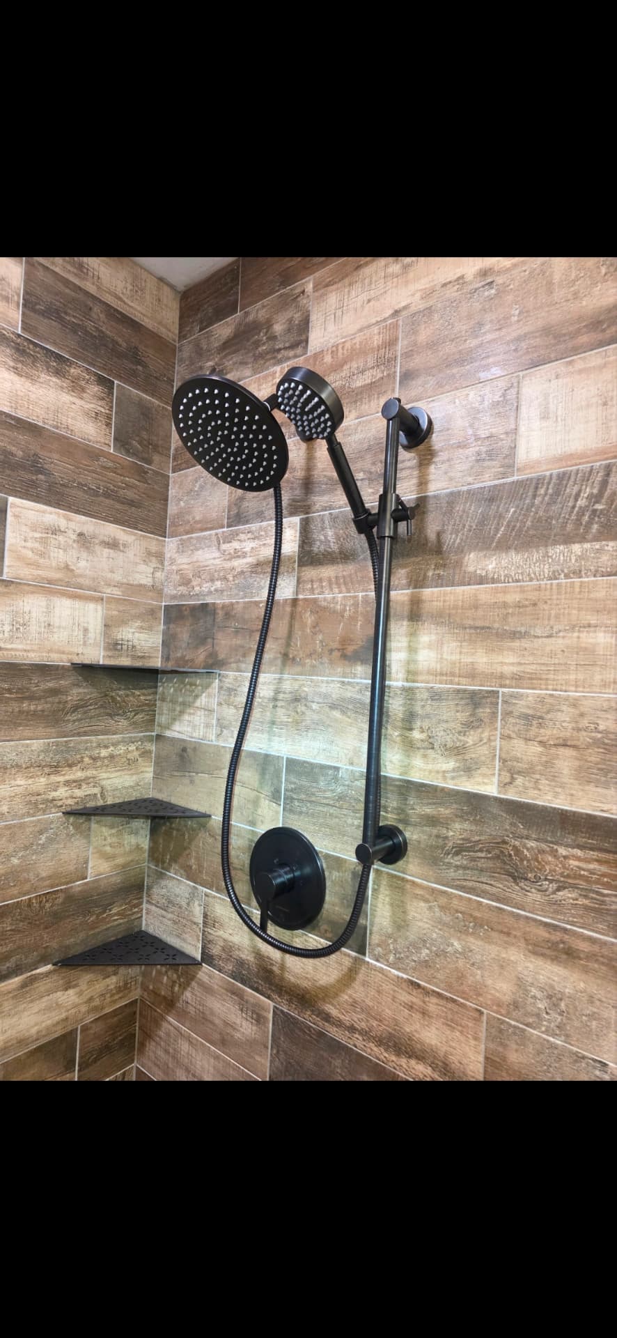 Matte black rainfall shower head and hand shower on wood-look tile