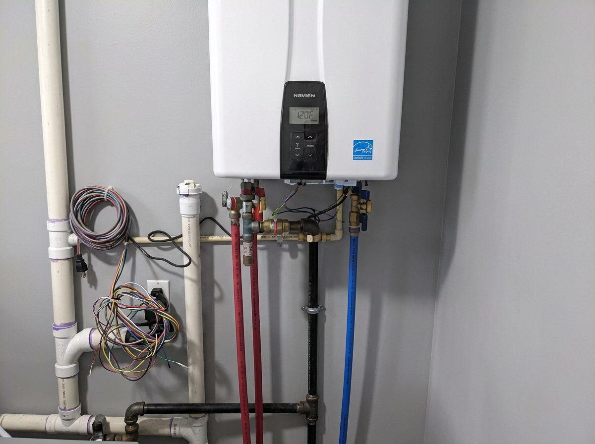 Wall-mounted residential tankless water heater with organized hot, cold and gas connections